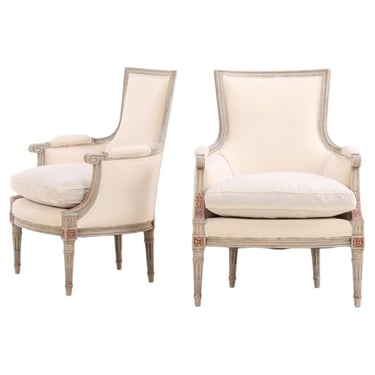 A pair of Louis XVI style grey painted and partial gilt Bergere chairs, C. 1940.
