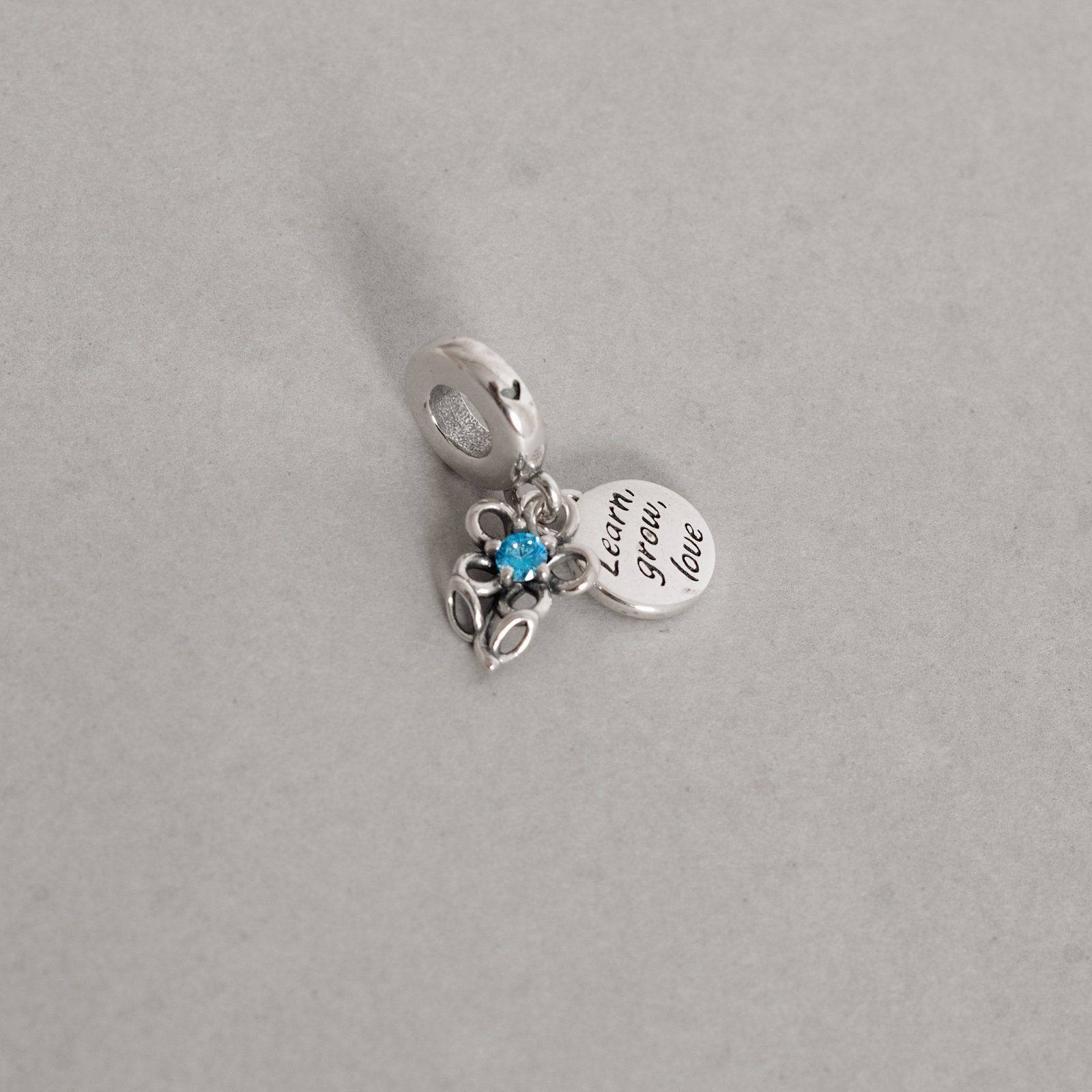 Berloque pingentes flor com zircônia azul e placa learn, grow, love envelhecido