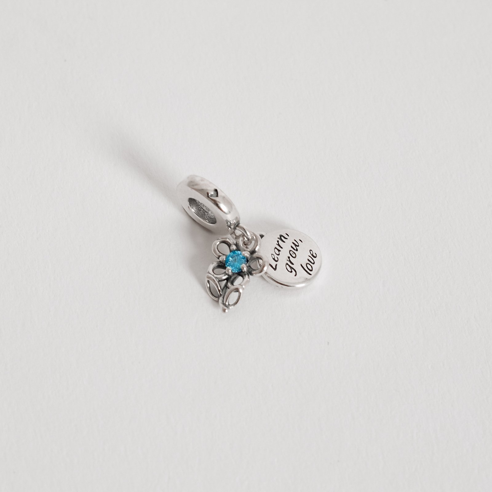Berloque pingentes flor com zircônia azul e placa learn, grow, love envelhecido