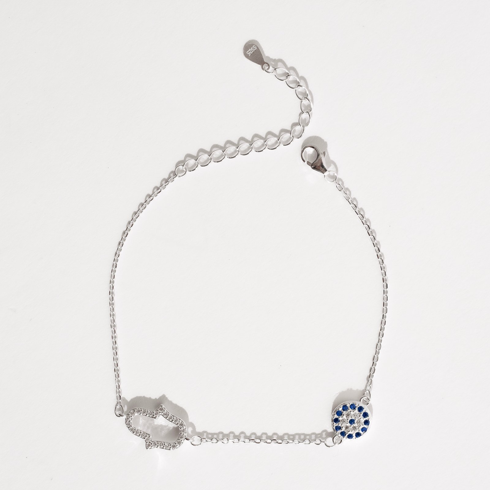 Pulseira entremeios mão vazada e olho grego cravejados