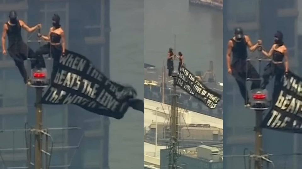 Dos encapuchados cuelgan pancarta por la paz en el Empire State