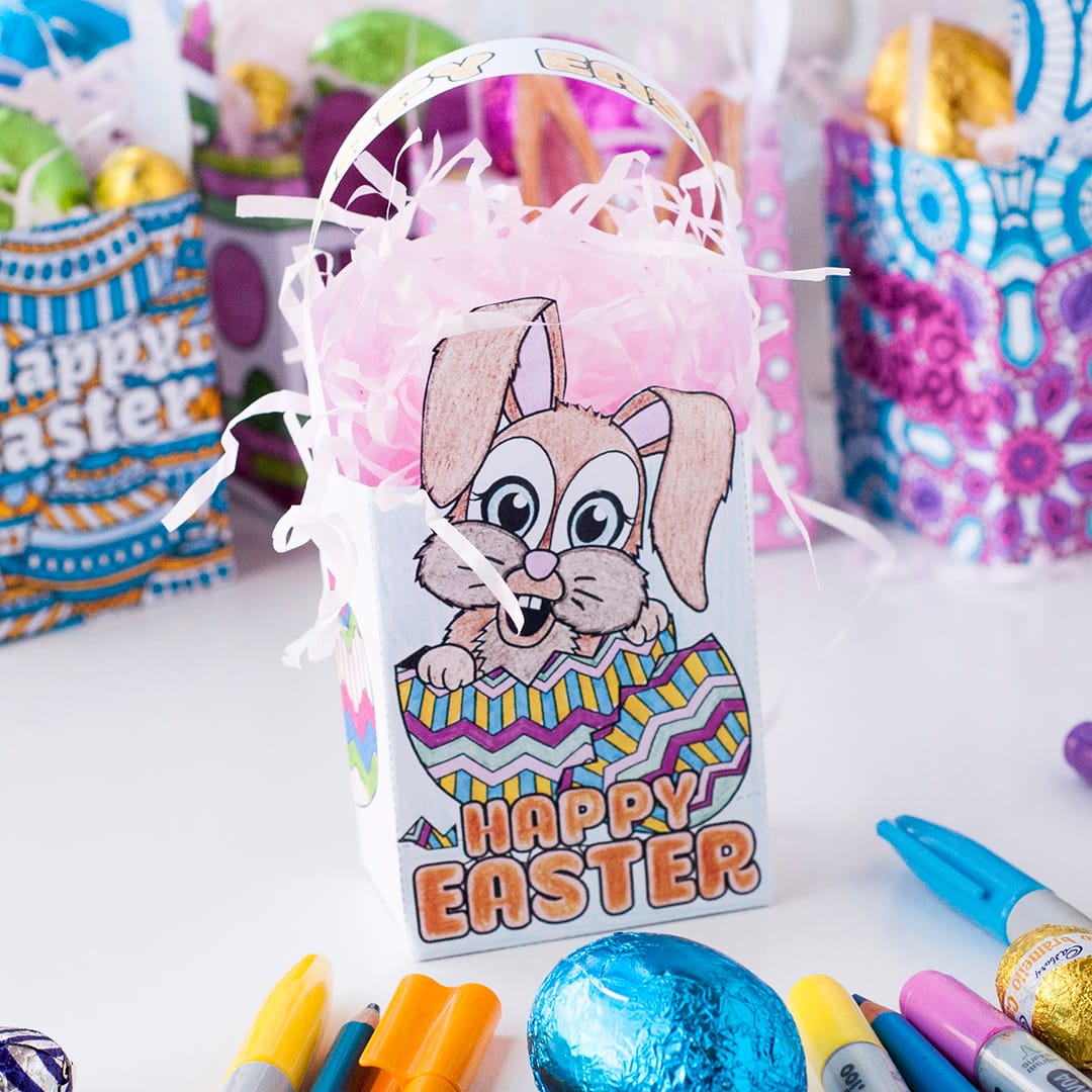 A do it yourself mini Easter gift bag with a picture of a rabbit behind a collection of colored pens and pencils