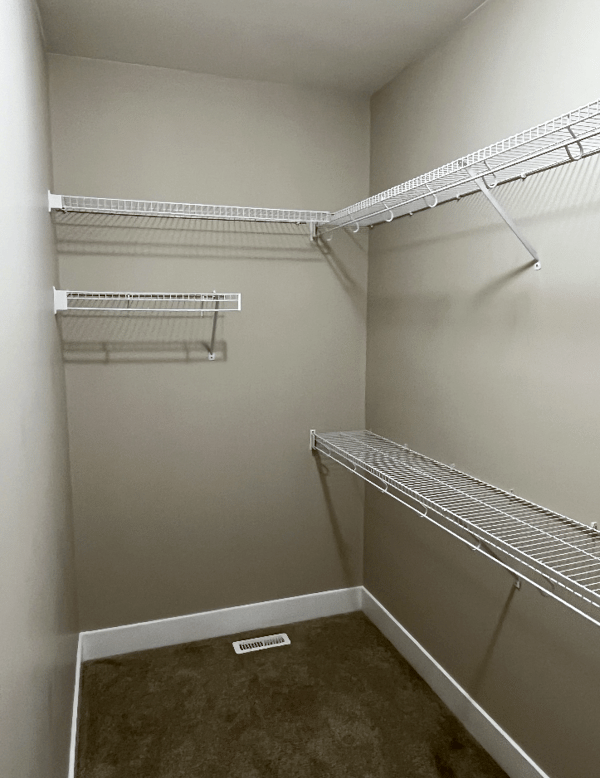 A freshly painted walk-in closet with a clean beige finish on the walls, complemented by white shelving and baseboards. The professional paint job ensures smooth and even coverage, enhancing the overall look and feel of the space.