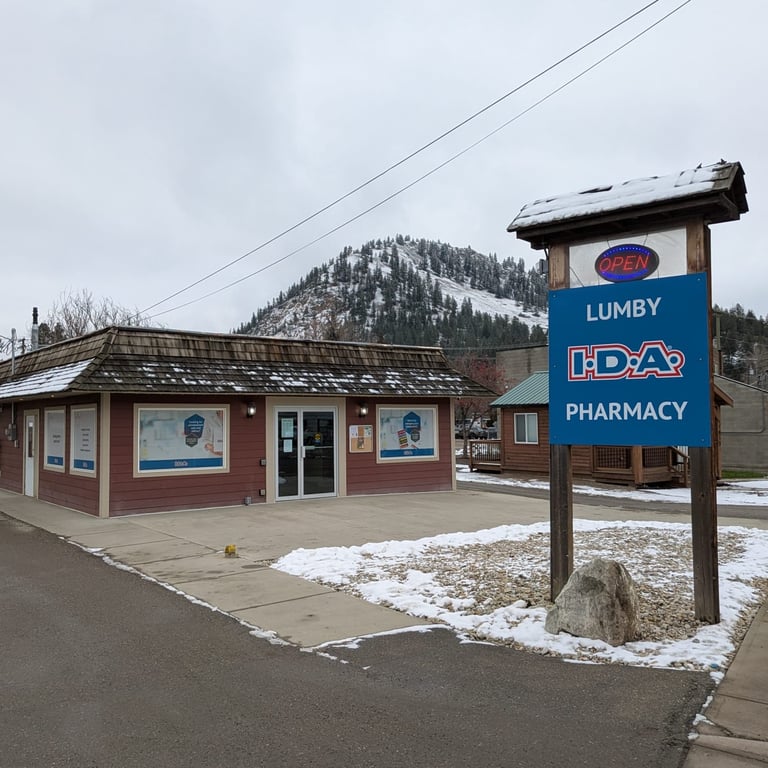 Lumby I.D.A. Pharmacy exterior with a blue sign, snow-covered ground, and a mountainous landscape in the background