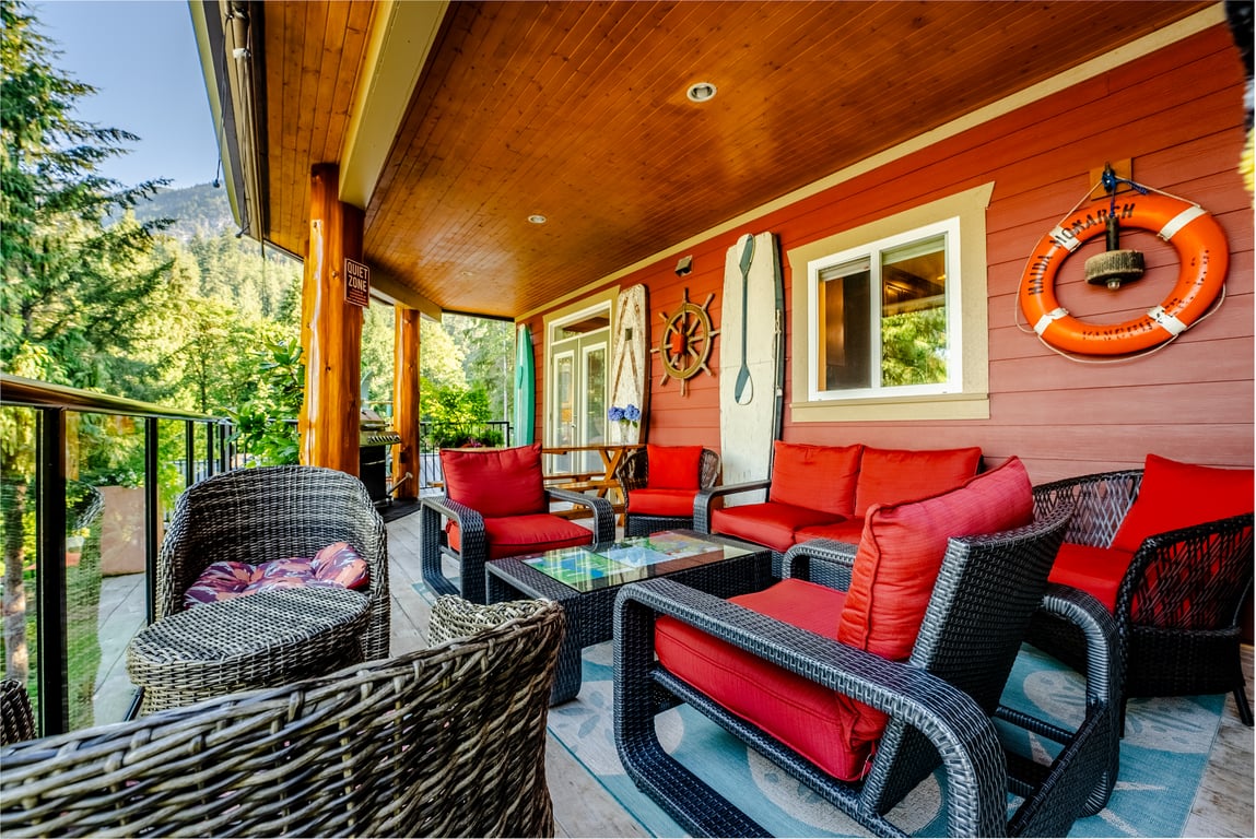 Covered deck with red cushioned patio furniture overlooking the trees