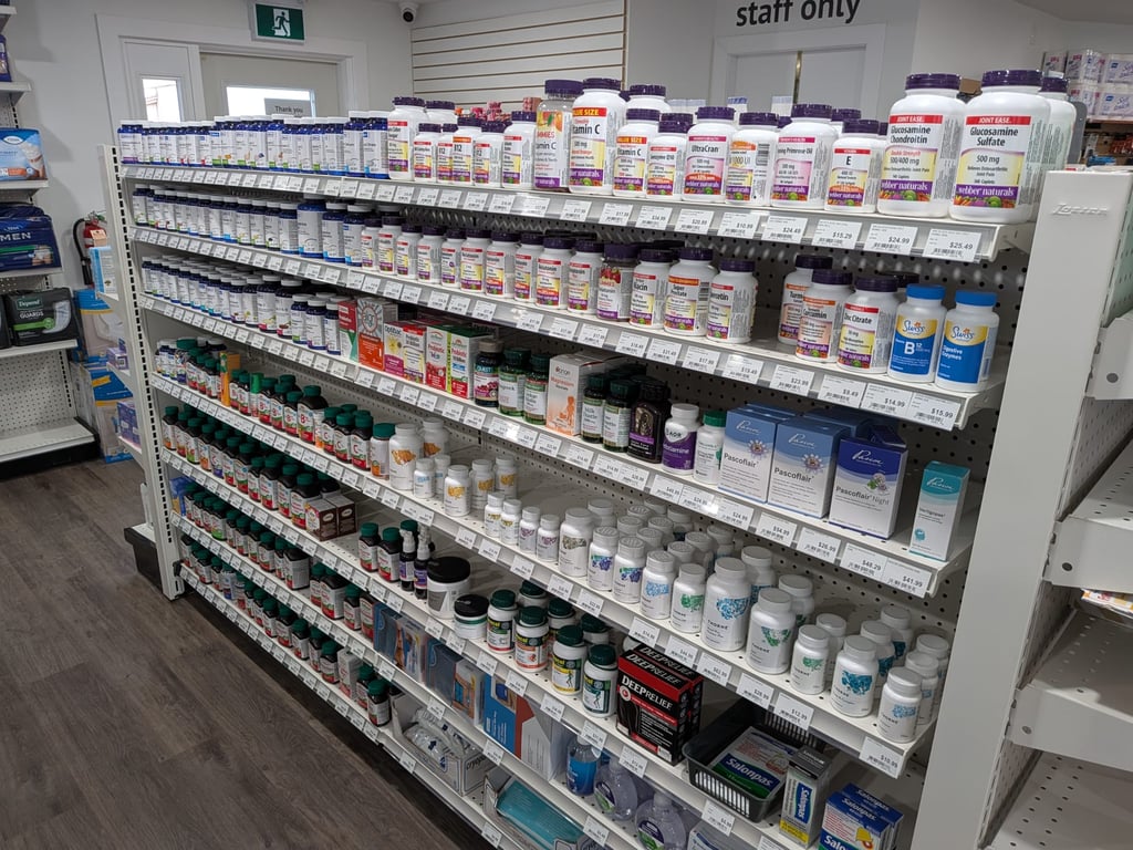 Pharmacy shelves stocked with vitamins, supplements, and natural health products in various bottles and packaging.