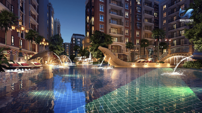 Expansive resort-style swimming pool featuring decorative statues, fountains, and beautifully lit buildings at night.