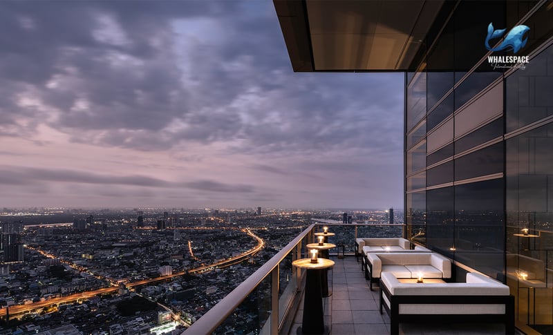 Elegant rooftop lounge area with comfortable outdoor seating and expansive city skyline views at dusk.
