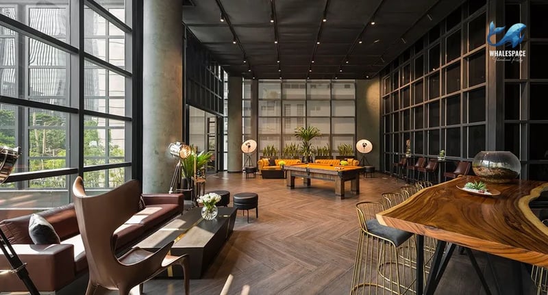 Sophisticated lounge space featuring luxurious brown sofas, a billiards table, and a live-edge table with bar stools, illuminated by stylish lamps.