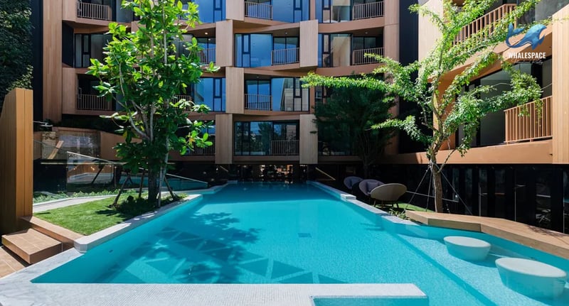 An inviting outdoor swimming pool with integrated seating areas surrounded by lush greenery and modern architecture.