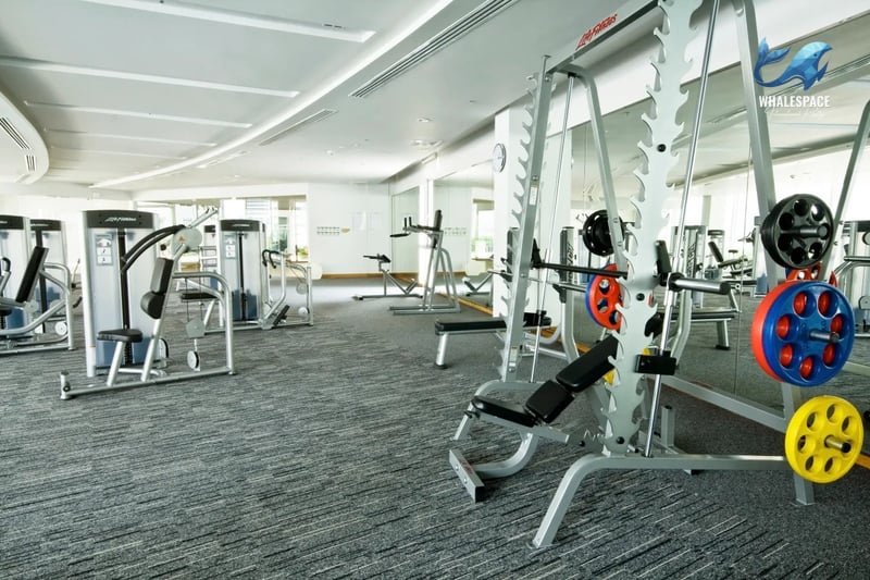 Gym featuring weight machines and free weights with mirrored walls.