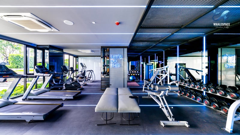 Well-equipped fitness center with various exercise machines and free weights, featuring ambient lighting