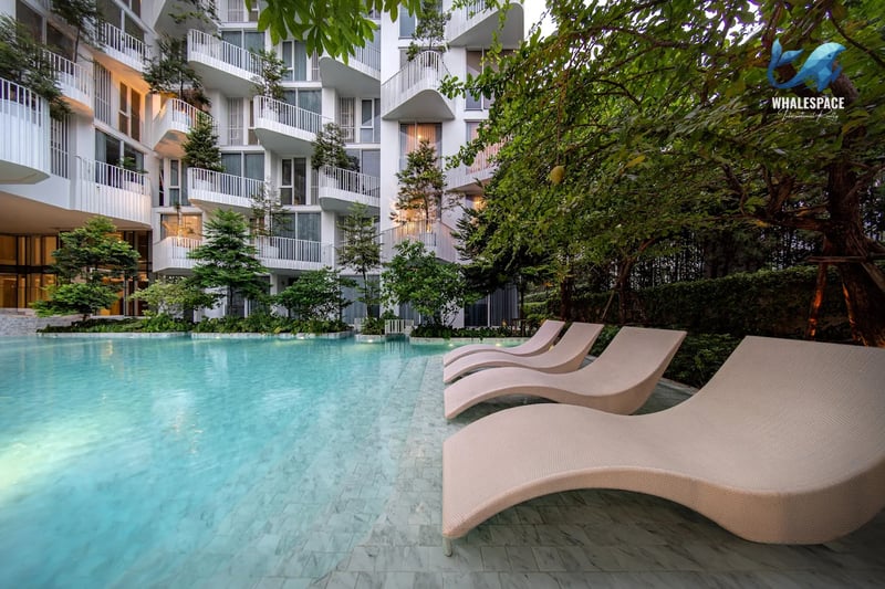 Serene swimming pool with modern lounge chairs and lush greenery, overlooking the building's unique facade.