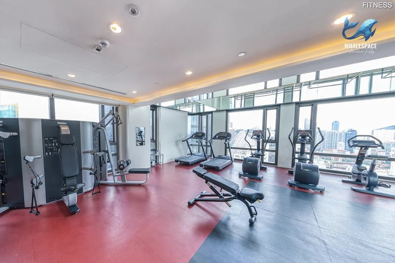 Well-equipped fitness center with a variety of cardio and strength training machines, offering city views through large windows.