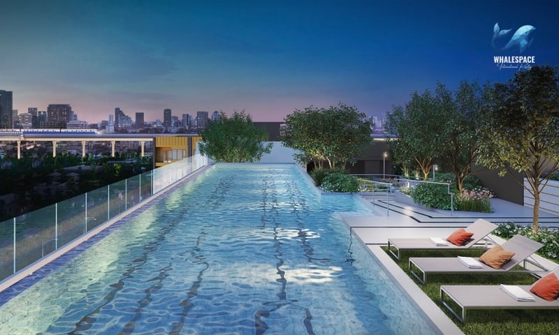 Rooftop swimming pool with city skyline views at twilight, surrounded by modern lounge chairs and lush greenery.