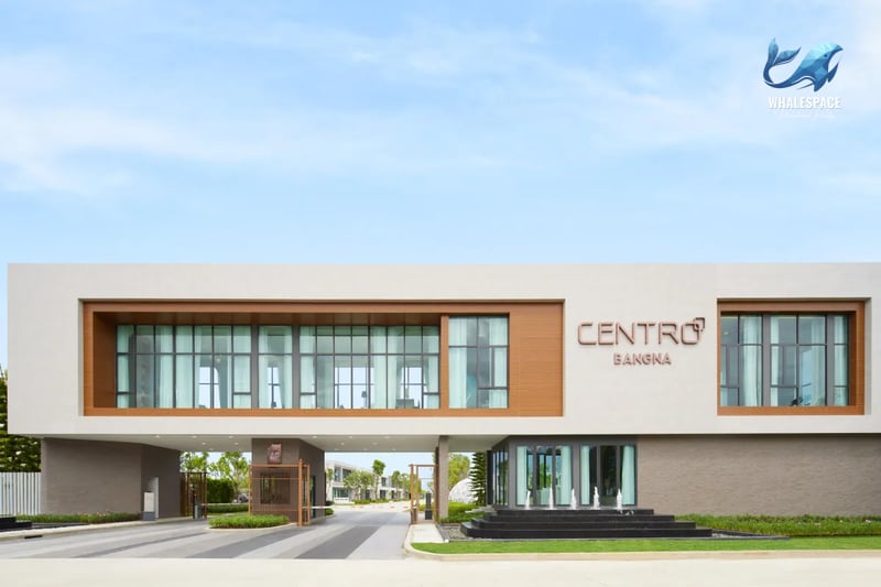 Modern entrance gate to a residential project, featuring a stylish clubhouse building with large windows and a water feature.