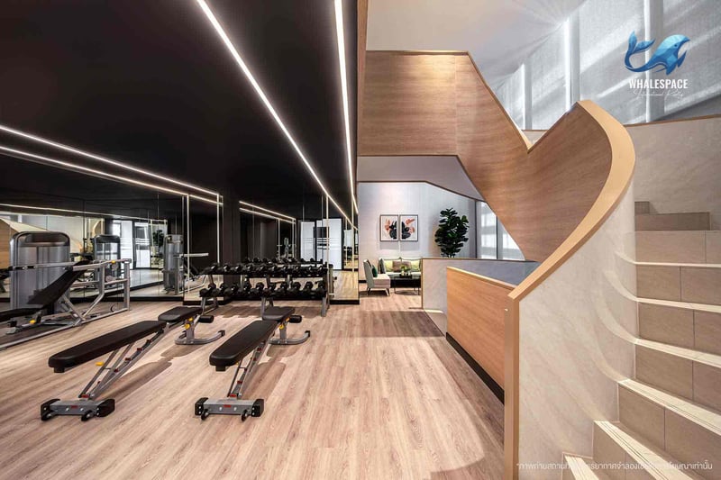 Well-equipped fitness center featuring a variety of weight machines and dumbbells, with a stylish staircase in the background.