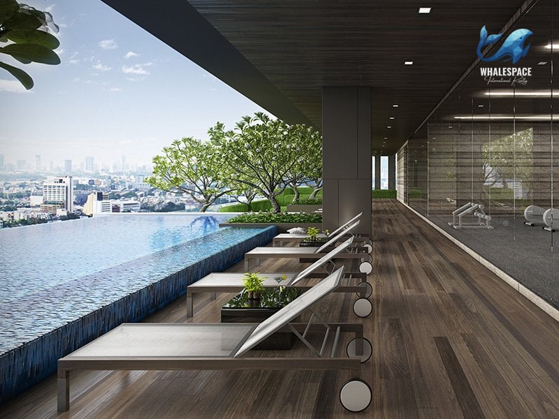Infinity pool with city views and lounge chairs, adjacent to a fitness center.
