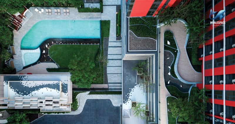 Aerial view of a resort-style swimming pool with surrounding gardens and seating areas.