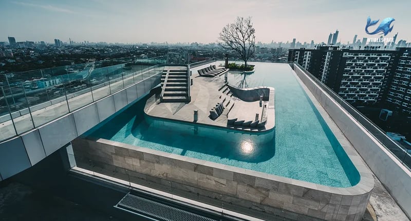Expansive rooftop pool with a unique tiered design and chaise lounges, overlooking the cityscape.