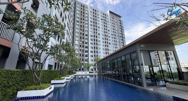 Modern condominium buildings overlooking a serene swimming pool and glass-walled fitness center.