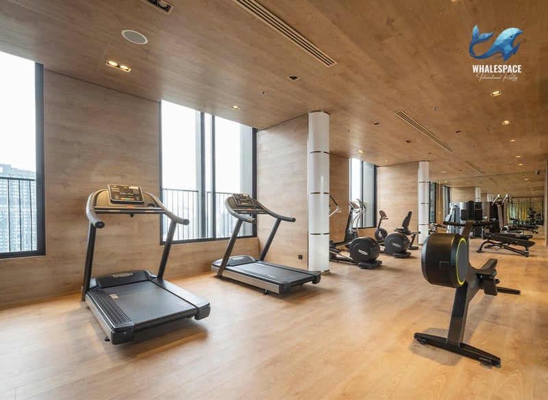 Well-equipped fitness center with treadmills, ellipticals, and rowing machines, featuring wood-paneled walls