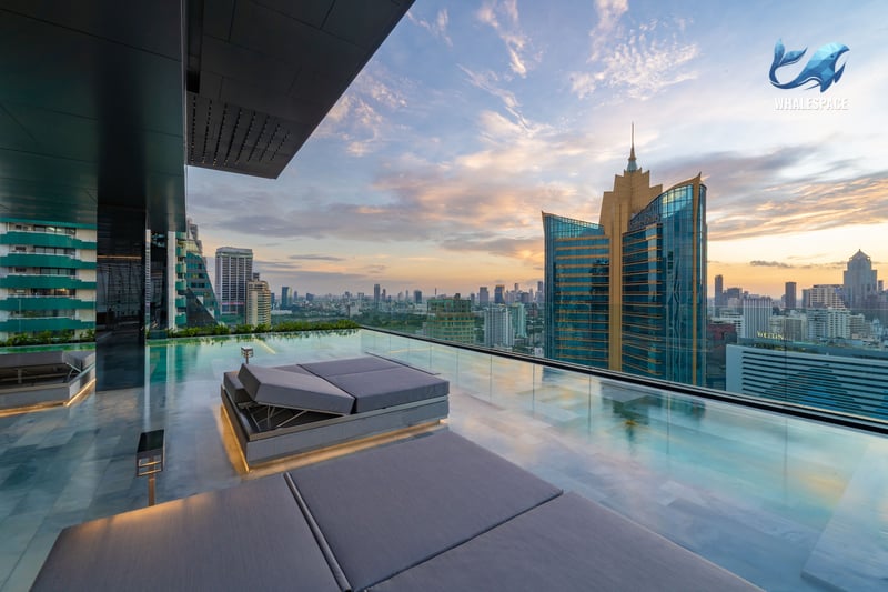 Infinity pool with sundeck and panoramic city skyline view at sunset