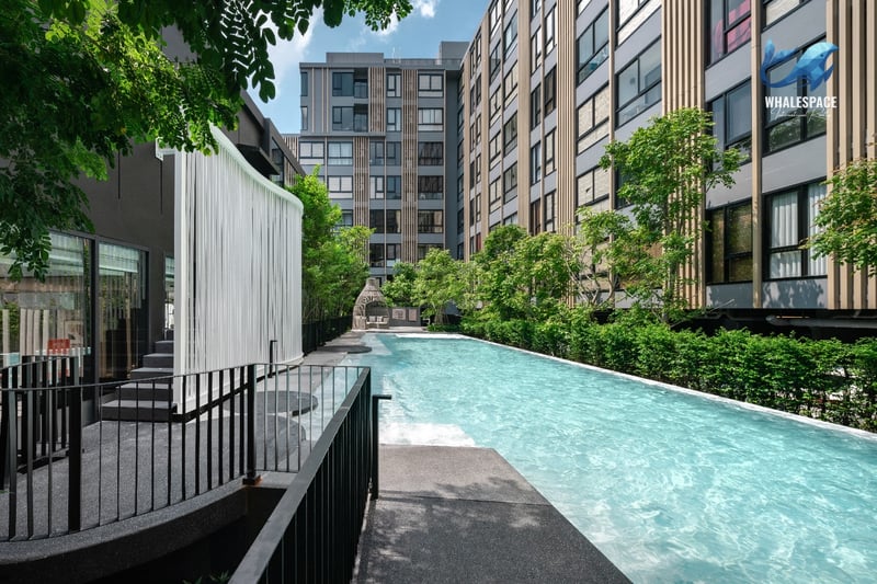 Outdoor lap pool surrounded by lush green landscaping and modern residential buildings.
