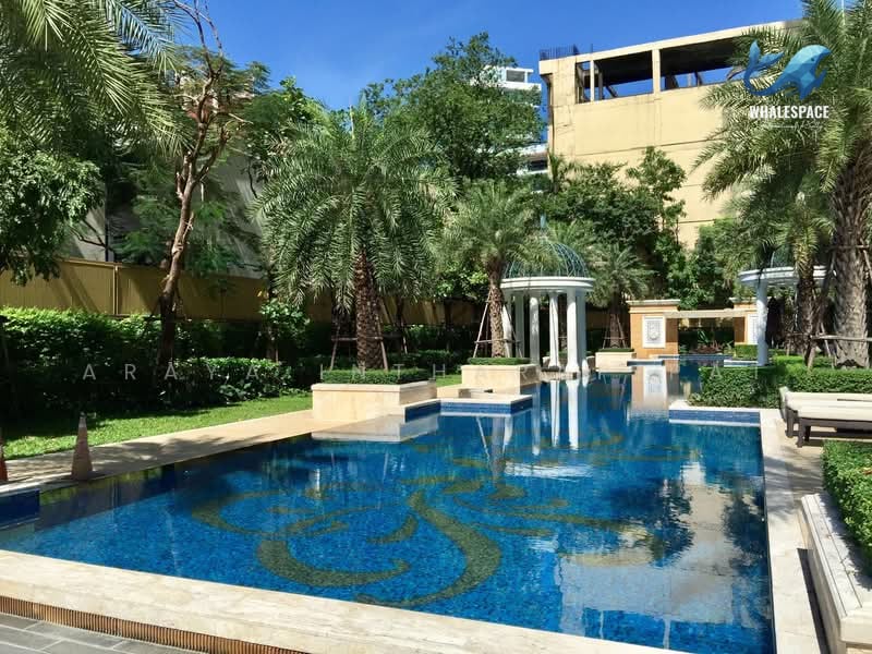 Outdoor swimming pool with decorative mosaic tiling, surrounded by lush tropical garden and elegant palm trees.