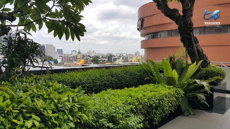 Lush green garden area with trimmed hedges and trees, overlooking the city skyline.
