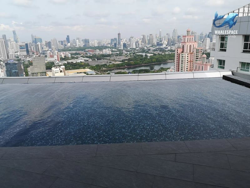 Infinity pool on a high floor, offering a daytime panoramic city skyline and a distant river view.