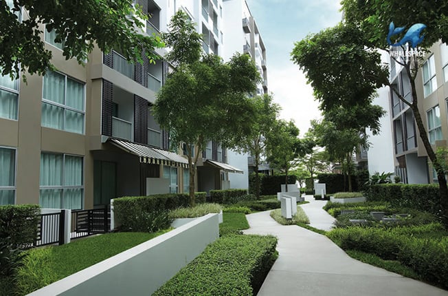 Lush green gardens and pathways surround the building exterior.