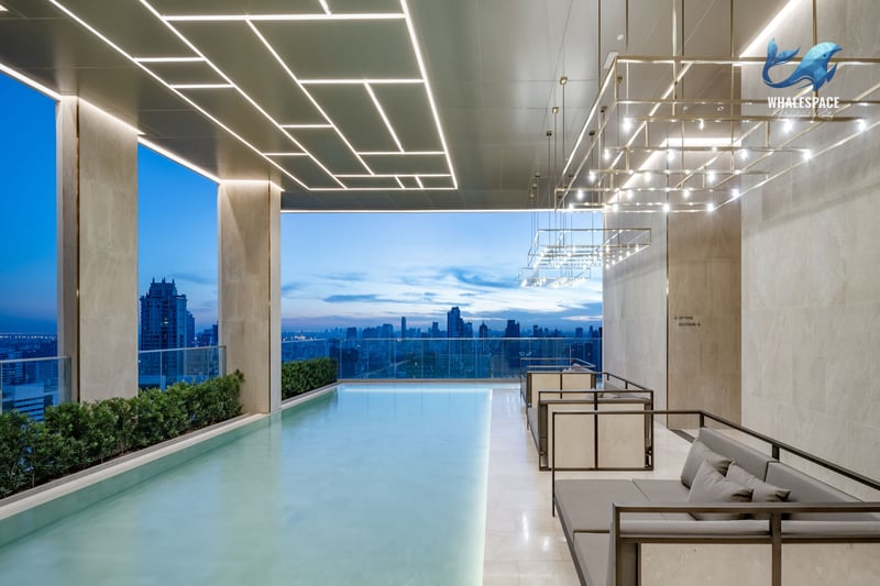 Luxurious indoor infinity pool with stunning city skyline views at dusk, featuring contemporary seating areas and ambient lighting.