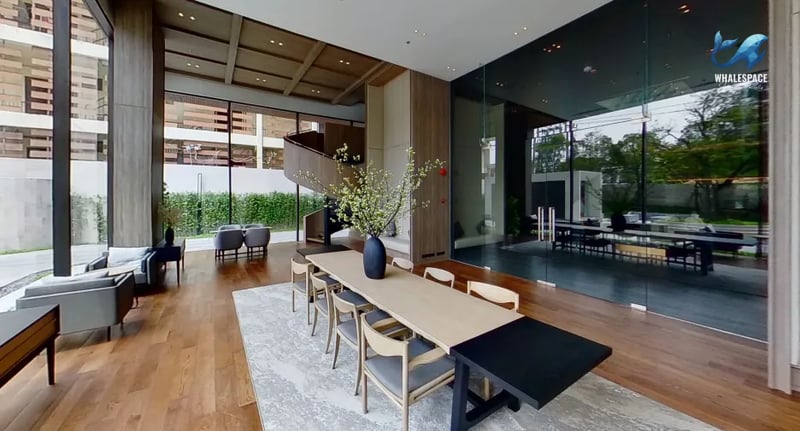 Bright and open lobby space featuring a long communal dining table, comfortable seating areas, and a unique spiral staircase.
