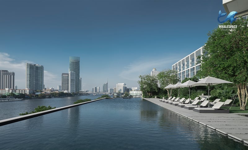 Riverside infinity pool with sun loungers and umbrellas, offering clear views of the city skyline and the Chao Phraya River.