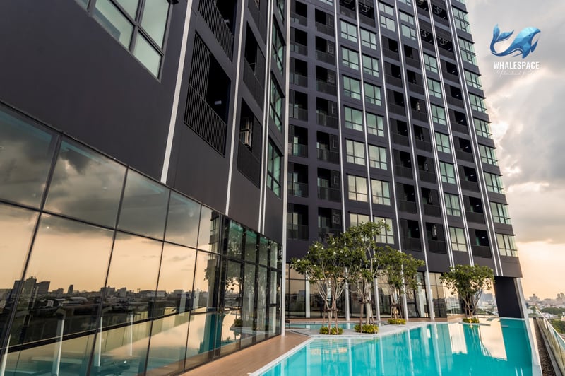 Modern black high-rise condominium exterior with an outdoor swimming pool and city reflections.