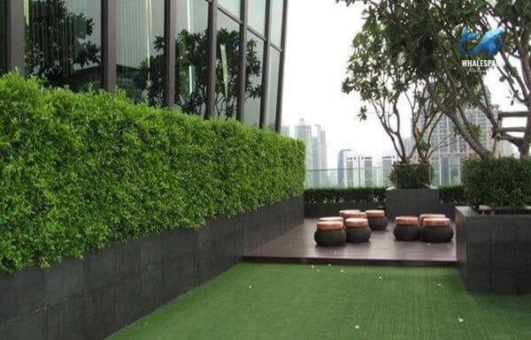 Lush green garden area with artificial turf and low wooden seating, providing a peaceful outdoor retreat.