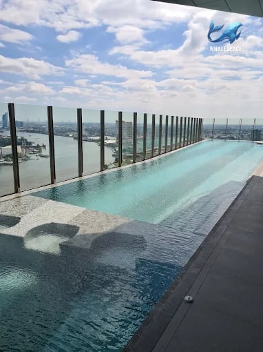 Infinity swimming pool with a stunning city and river view under a bright sky