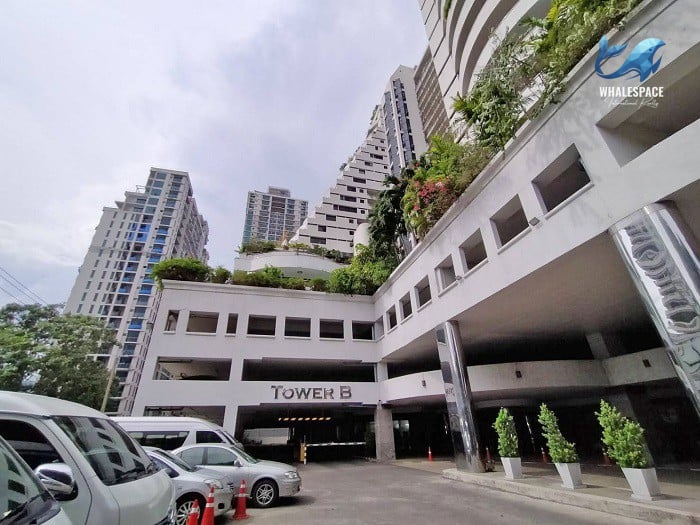 Entrance to Tower B parking, a multi-level structure with modern architecture and surrounding high-rise buildings.