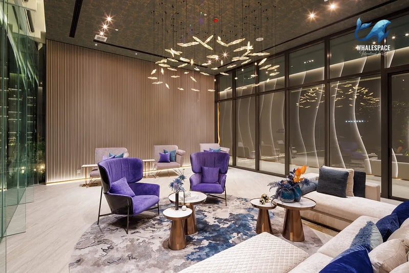 Sophisticated lounge space with plush purple armchairs, a large L-shaped sofa, and a distinctive artistic chandelier