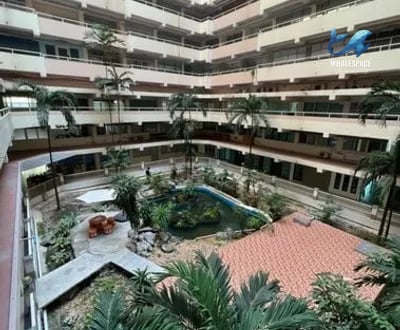 Aerial view of the courtyard showcasing a pond and tropical plants within a multi-story building.