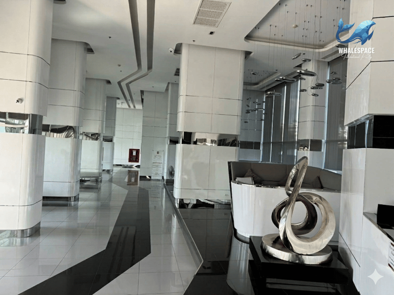 Sleek and spacious condominium lobby featuring contemporary black and white tiled floors, reflective columns, and artistic lighting fixtures above a curved seating area.