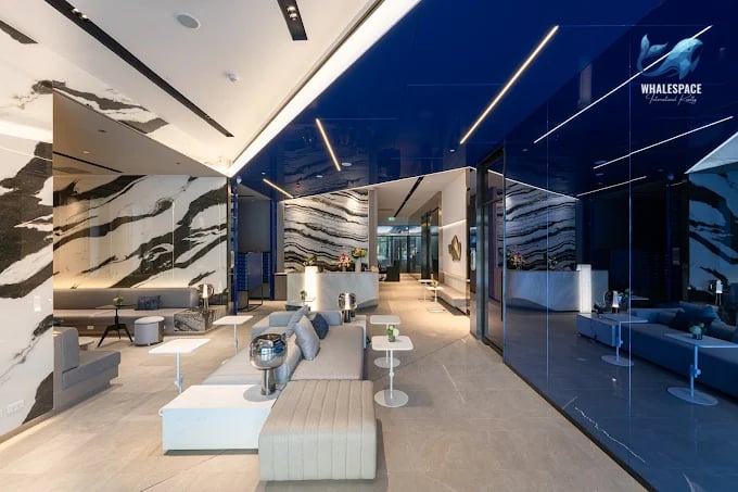 Luxurious and contemporary lobby with striking marble accents, a sleek blue ceiling, and comfortable seating areas.