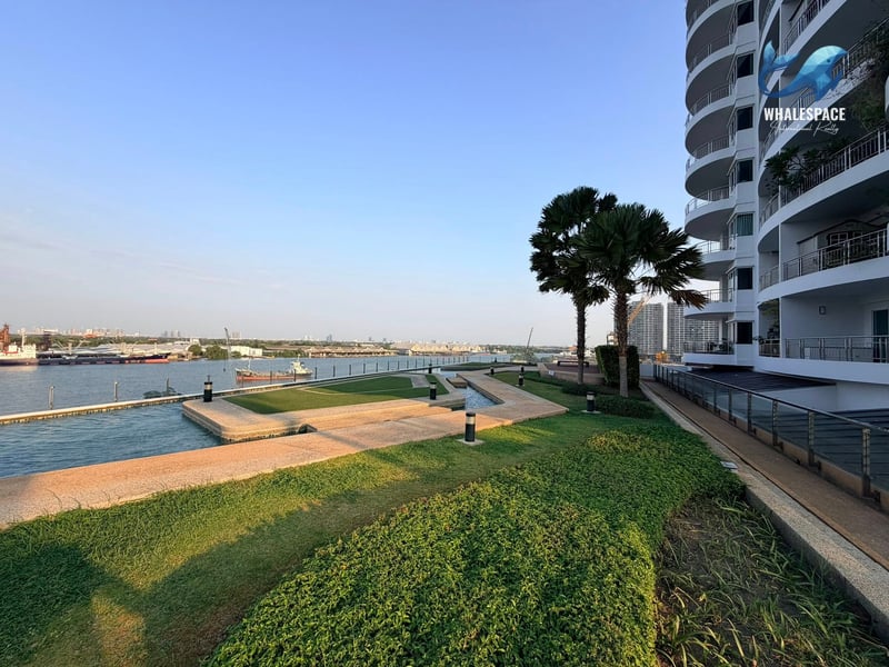 Landscaped garden area with manicured lawns and pathways next to a riverside building