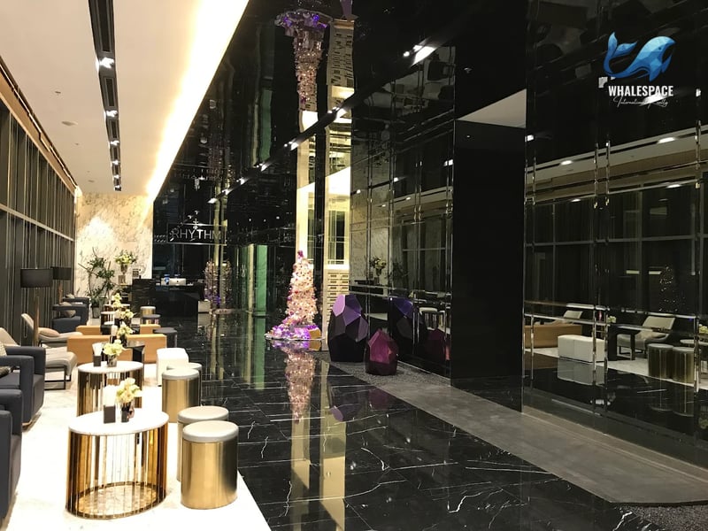 Luxurious lobby area featuring dark polished marble floors, reflective surfaces, and modern seating with elegant golden accent tables.