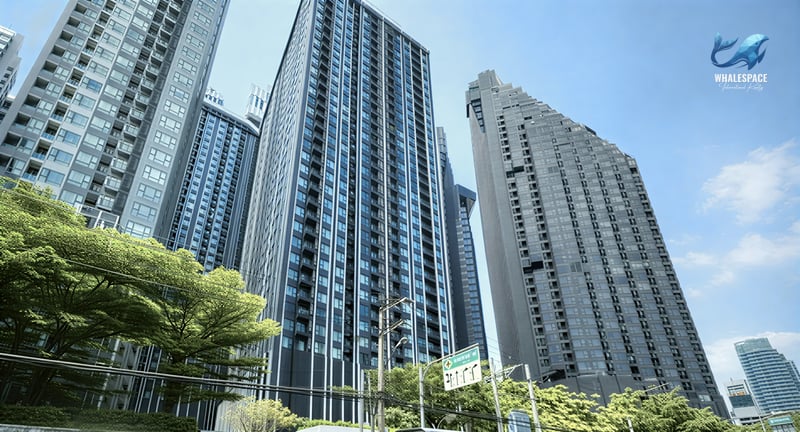 Modern high-rise condominiums under a clear blue sky, surrounded by lush greenery.