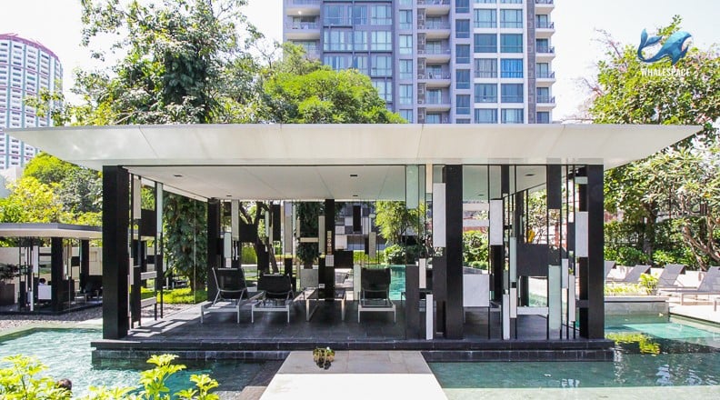 Stylish poolside pavilion with lounge chairs and decorative screens, set amidst lush green landscaping