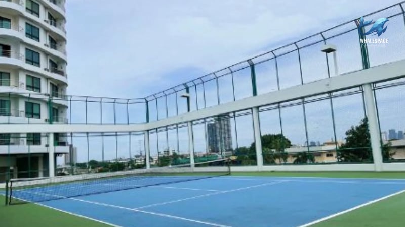 Outdoor tennis court with netting against a backdrop of city buildings