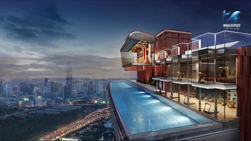 View of the expansive infinity pool and adjacent fitness center with cardio machines and city backdrop.
