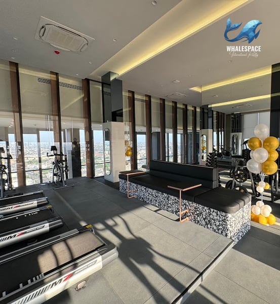 Modern fitness center featuring treadmills, cycling machines, and a lounge area with city views.